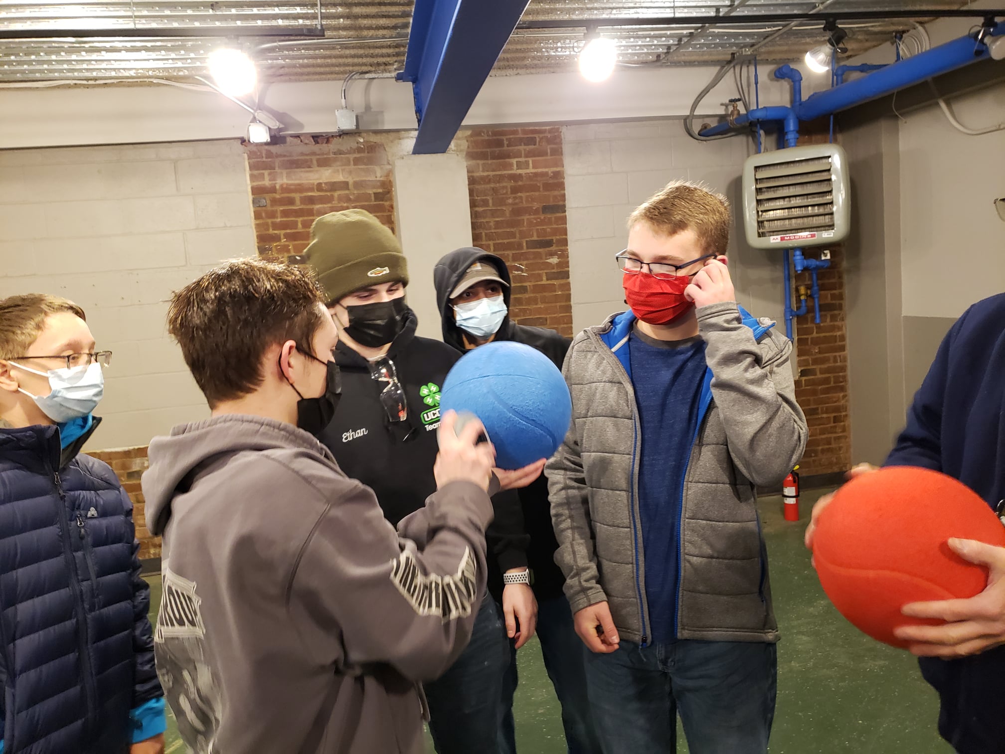 students standing meeting with game balls brainstorming robot design