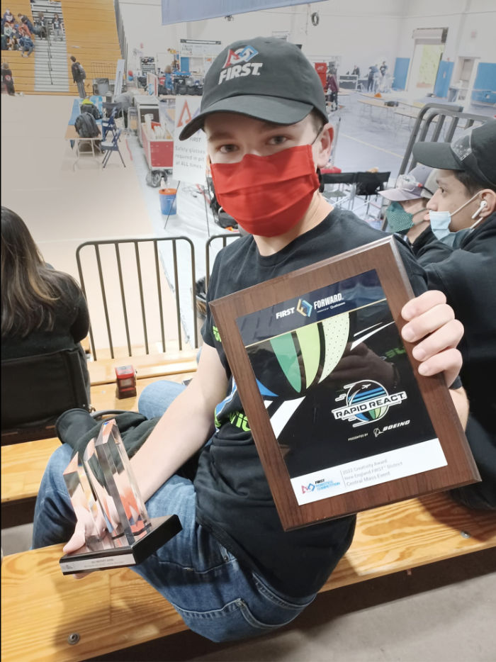 student holding trophy and award plaque at competition