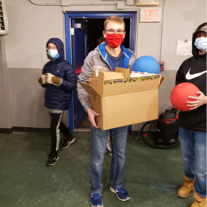 moving day, smiling student brings box through door