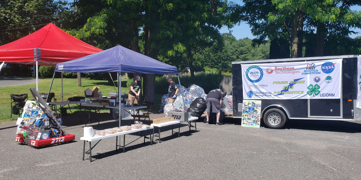 canopied tables, robot, and trailer on parking lot set up for can drive