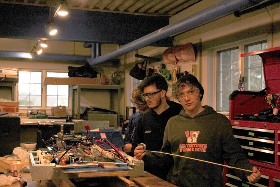 three students working on robot at shop bench