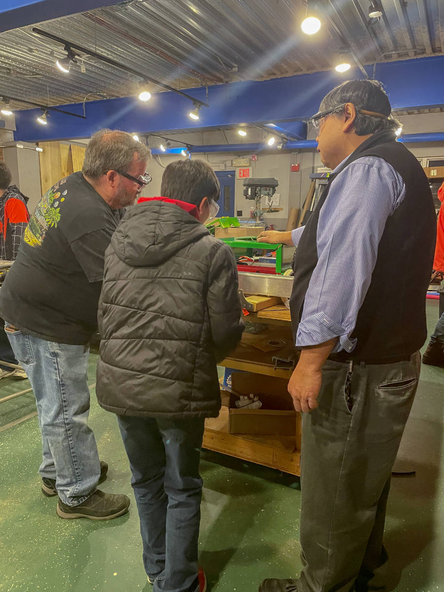 Two mentors and a student working on robot chassis