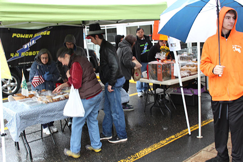 Bake Sale table with students and customers in the rain