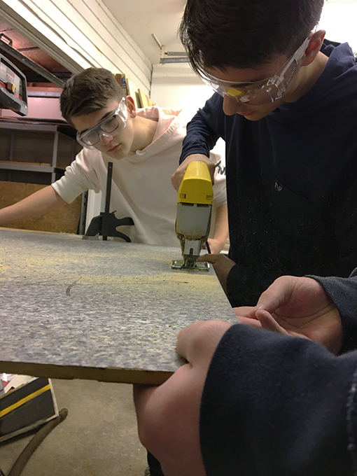 Students sawing a large board