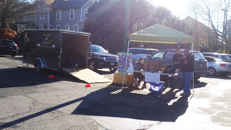 open trailer and tent with table in grocery store parking lot during food drive event