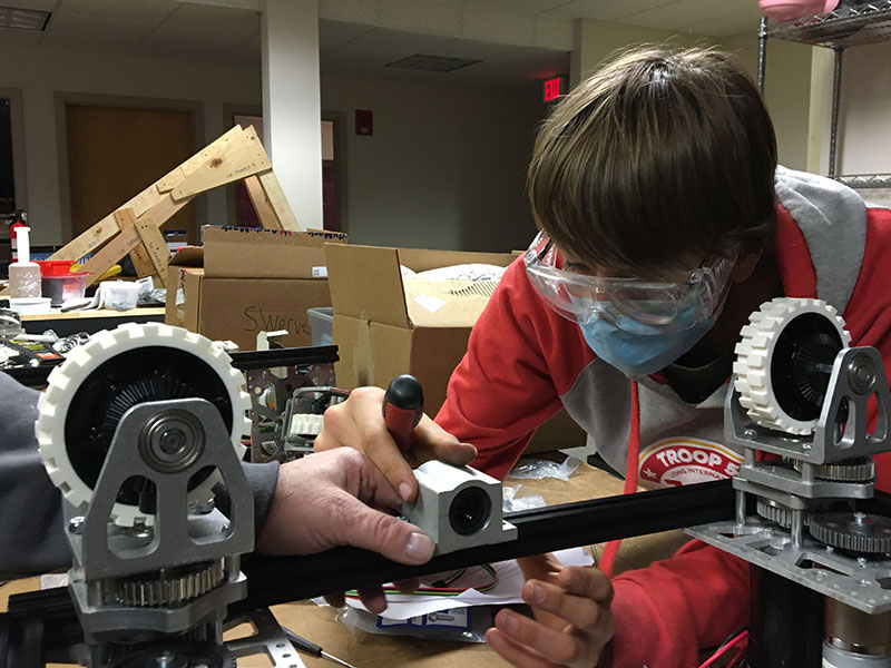 student at workbench installing robot component with mentor help