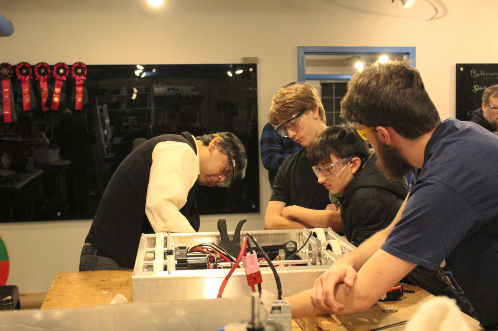 students and mentor working on drivetrain