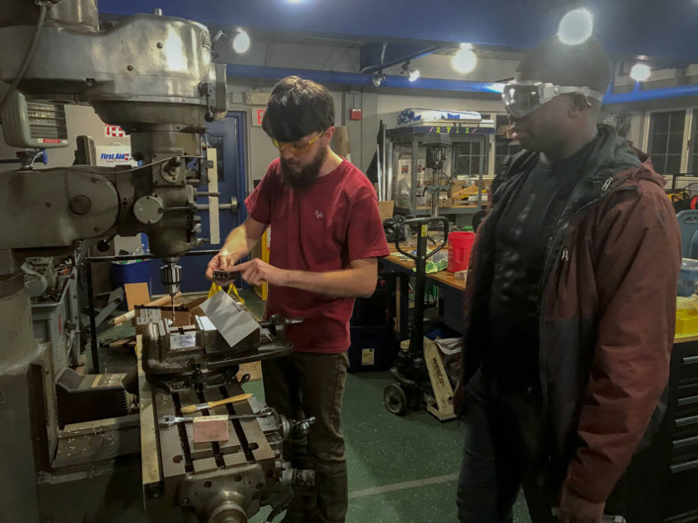young mentor teaching student to use the Bridgeport machine