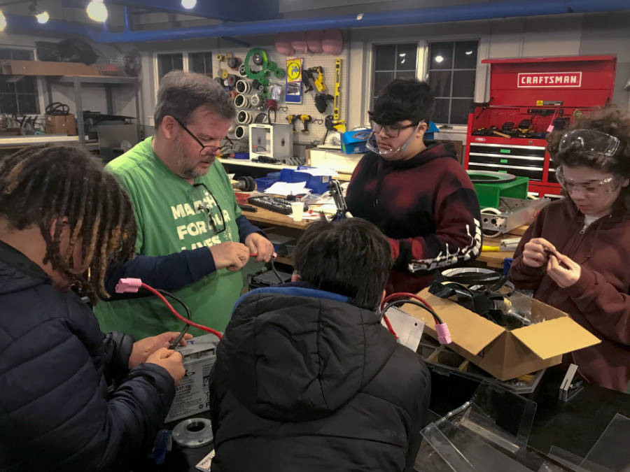 Four students and a mentor installing wires on batteries