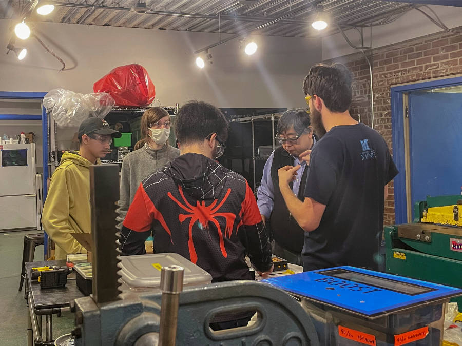 mentors and students around shop bench in discussion