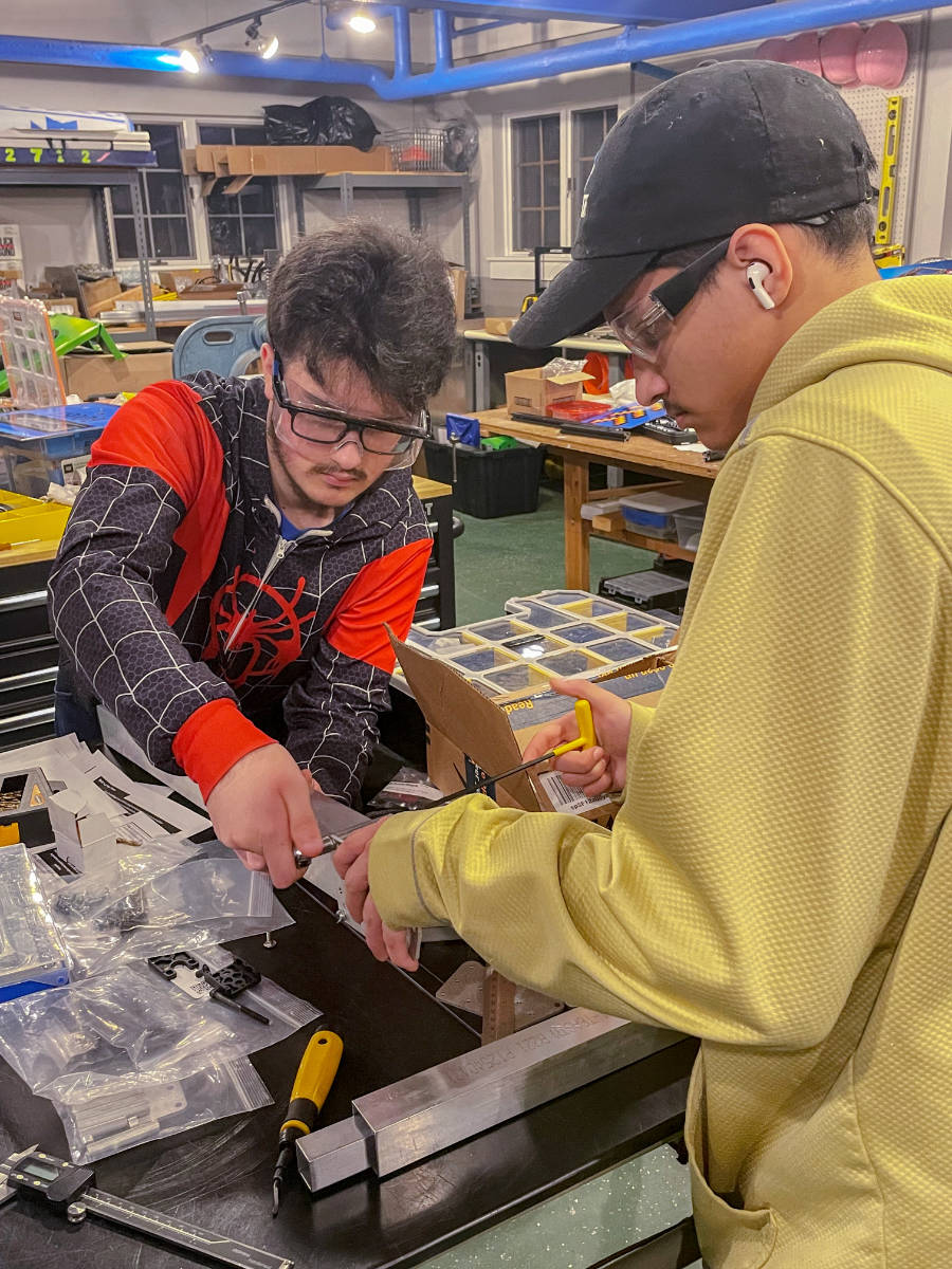 two students working on robot parts on shop bench