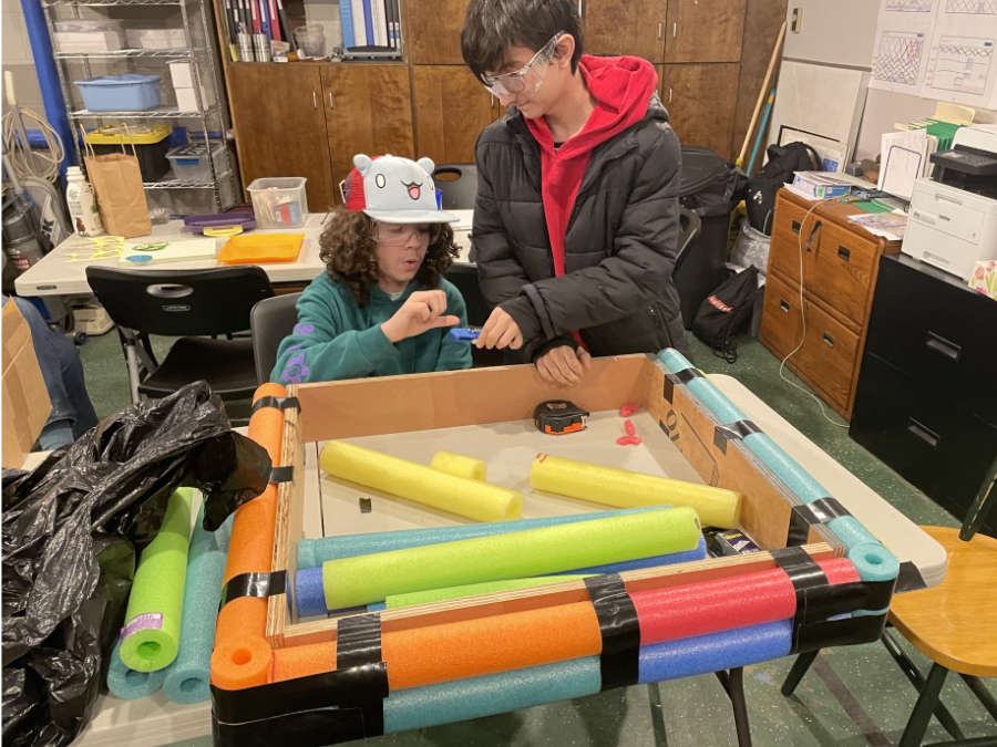 Two students working on building bumpers with pool noodles on wooden frame