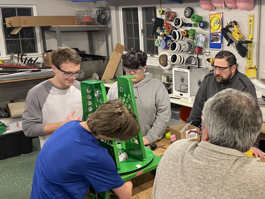 students and mentors working on robot turret on workbench